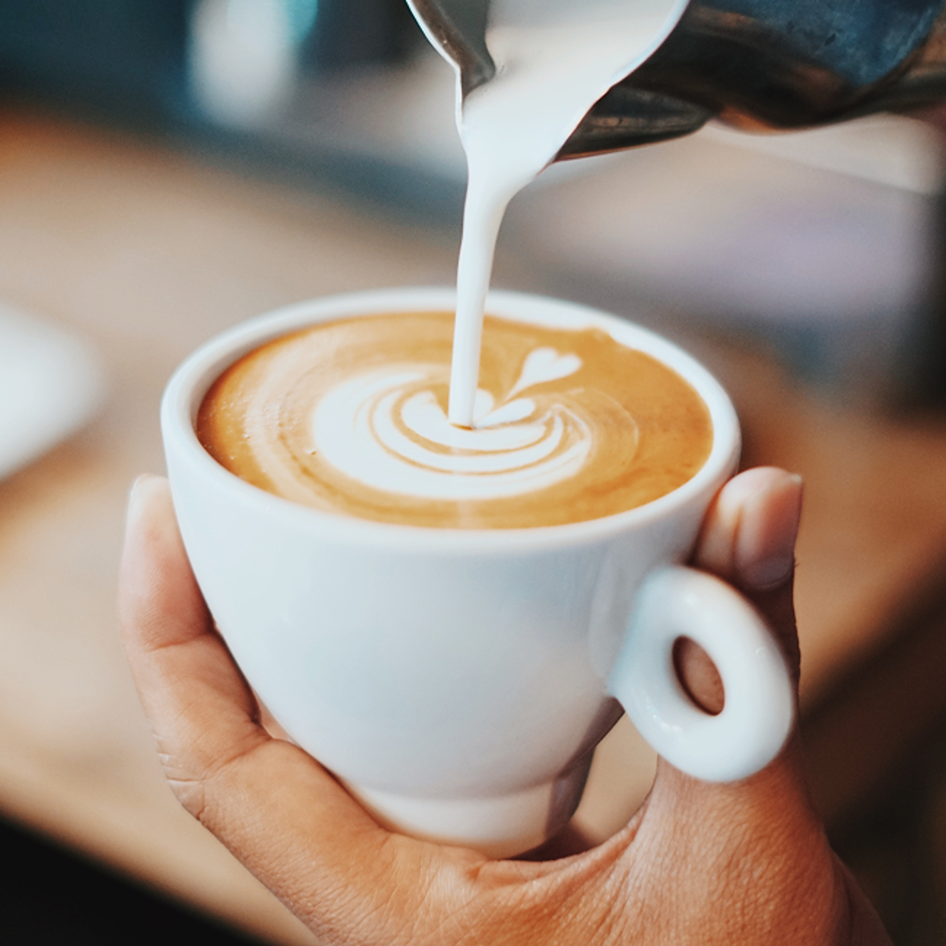 Milch wird in einen Cappuccino gegossen.