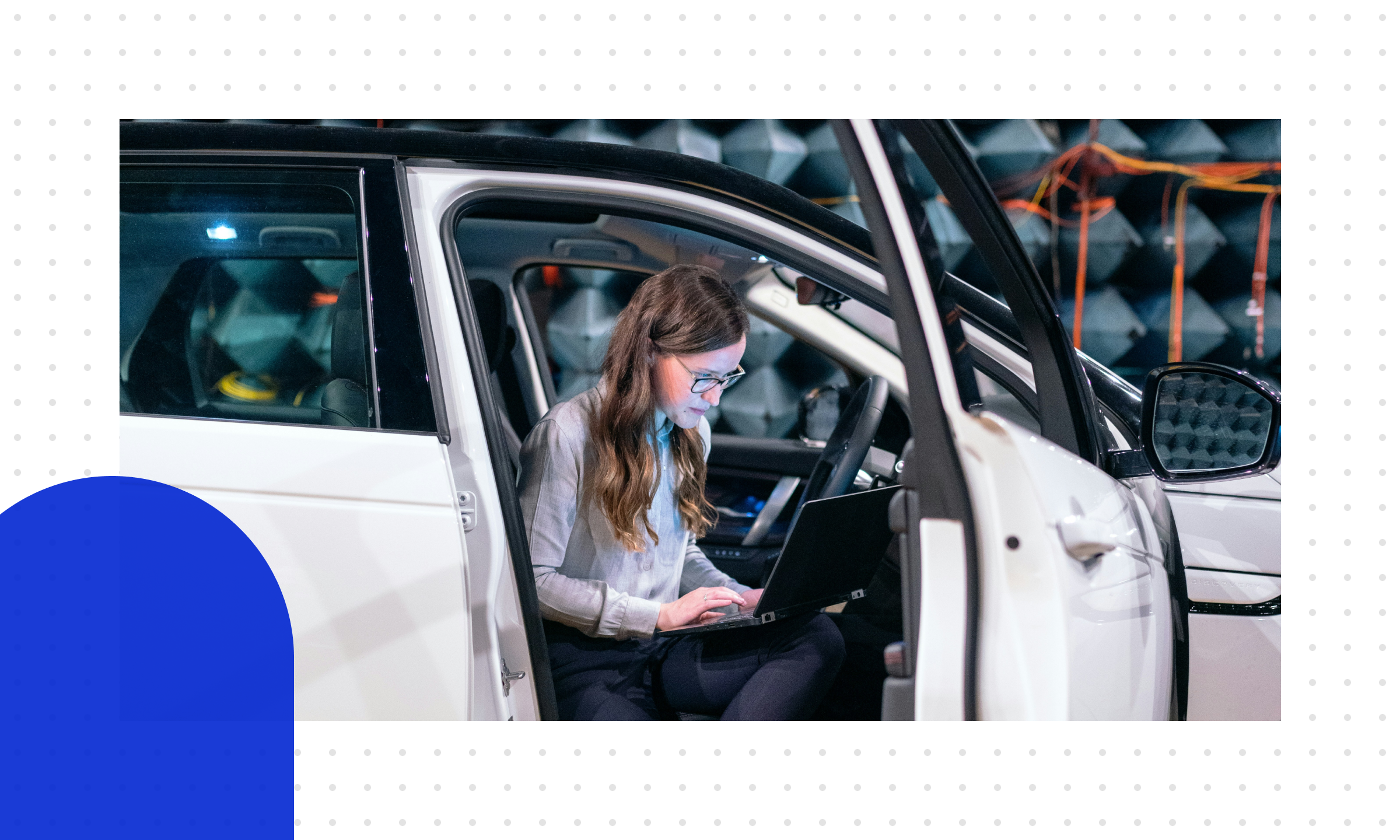  Eine Frau sitzt mit ihrem Laptop im Auto in einem Testlabor und beschäftigt sich mit den Trends der Automobilindustrie