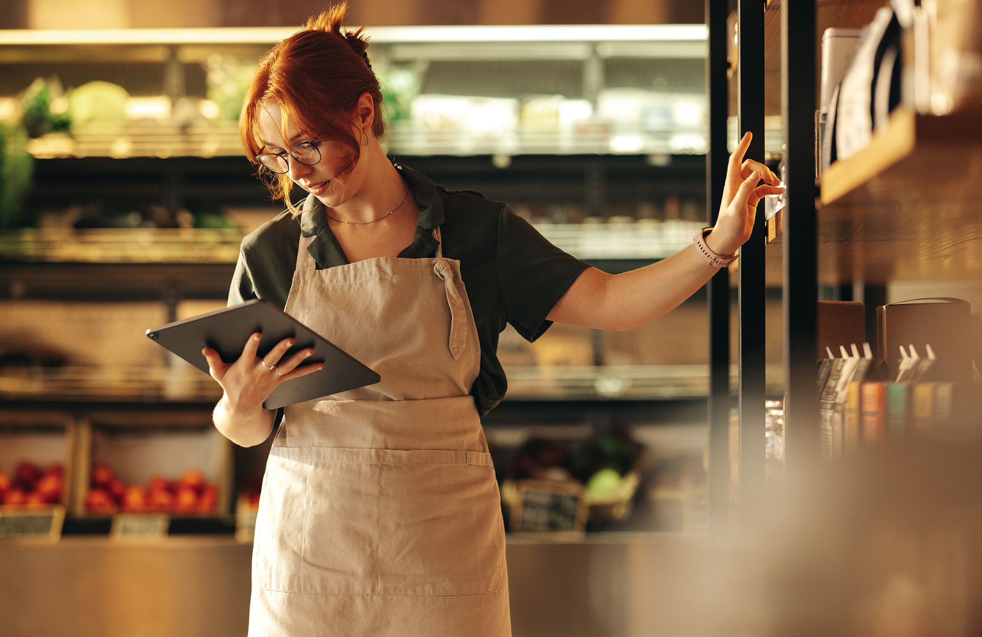 Verkäuferin steht mit Tablet mit Salesforce Consumer Goods Cloud an Warenregal.