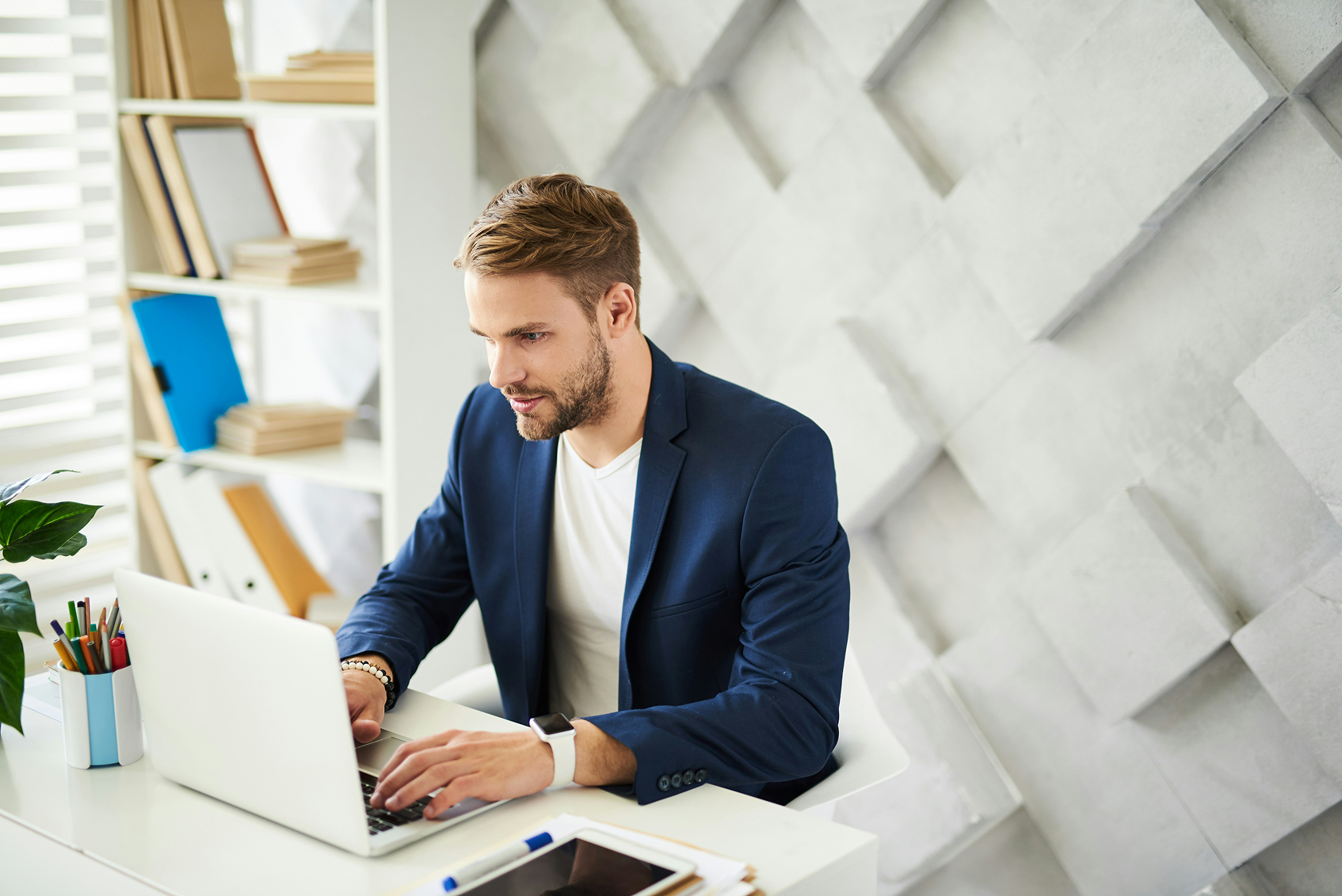 Mann mit blauem Anzug vor Laptop