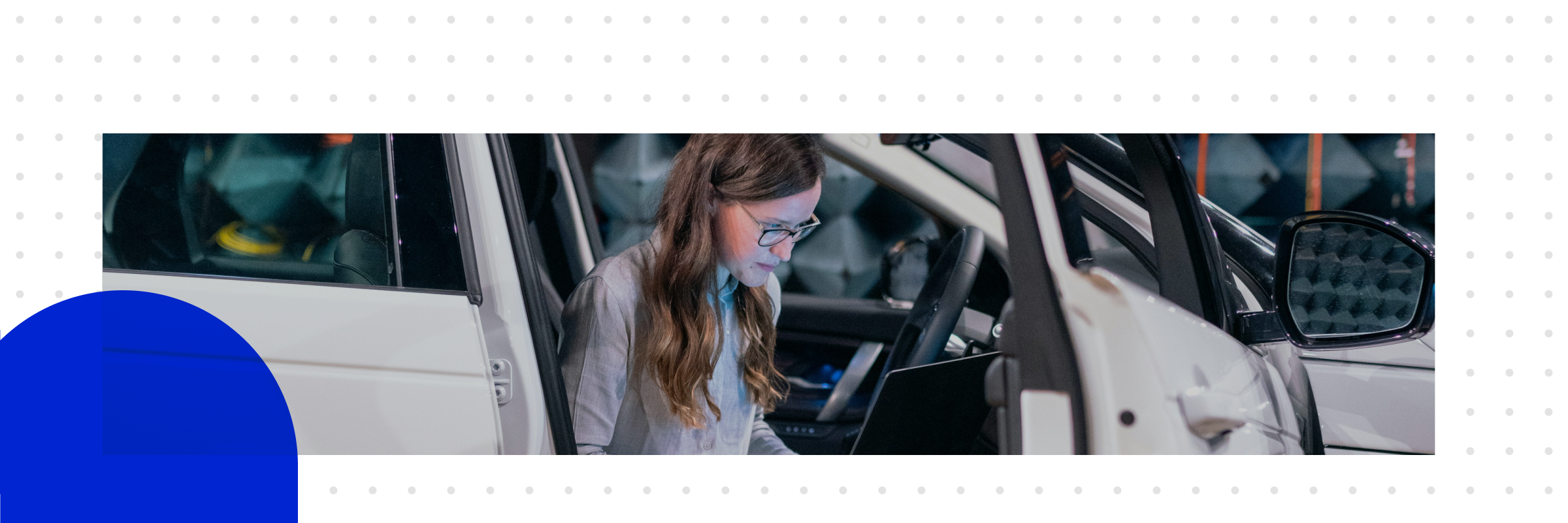  Eine Frau sitzt mit ihrem Laptop im Auto in einem Testlabor und beschäftigt sich mit den Trends der Automobilindustrie