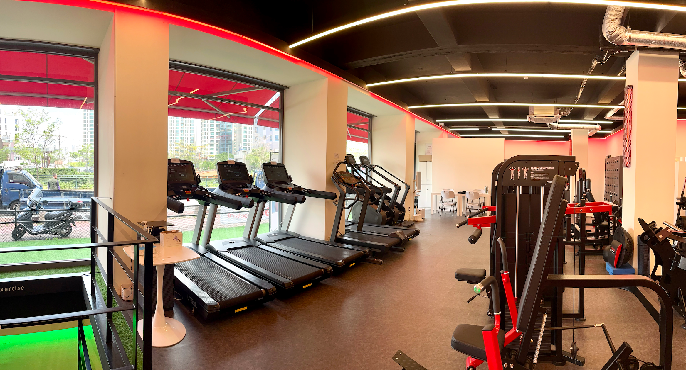 청계천을 뒷 배경으로 유산소, 무산소 기구가 보이는 헬스장 전경