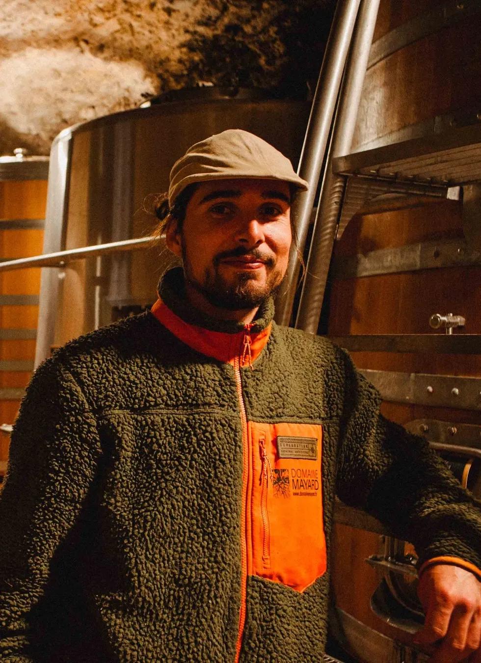 Vigneron souriant dans le chai, devant les cuves en bois