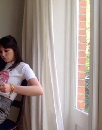 A woman with bangs reads a book titled 'The A-Z of Great Women Artists'.