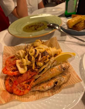 A plate of fried calamari, shrimp, and small fish with a lemon wedge.