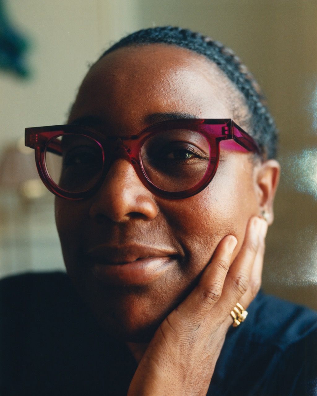 Mashama Bailey, Semaine Tastemaker. A smiling person with dark skin, wearing red glasses, rests a hand on their cheek.