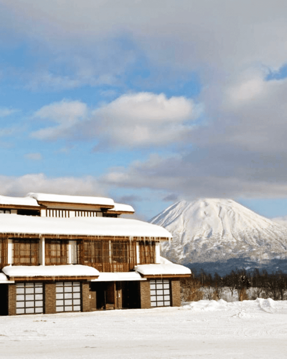 A snow-covered building with icicles and a large, snowy mountain in the background.