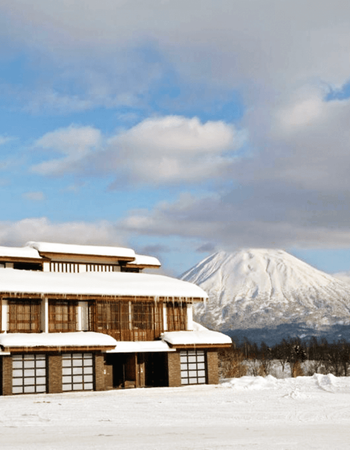 A snow-covered building with icicles and a large, snowy mountain in the background.