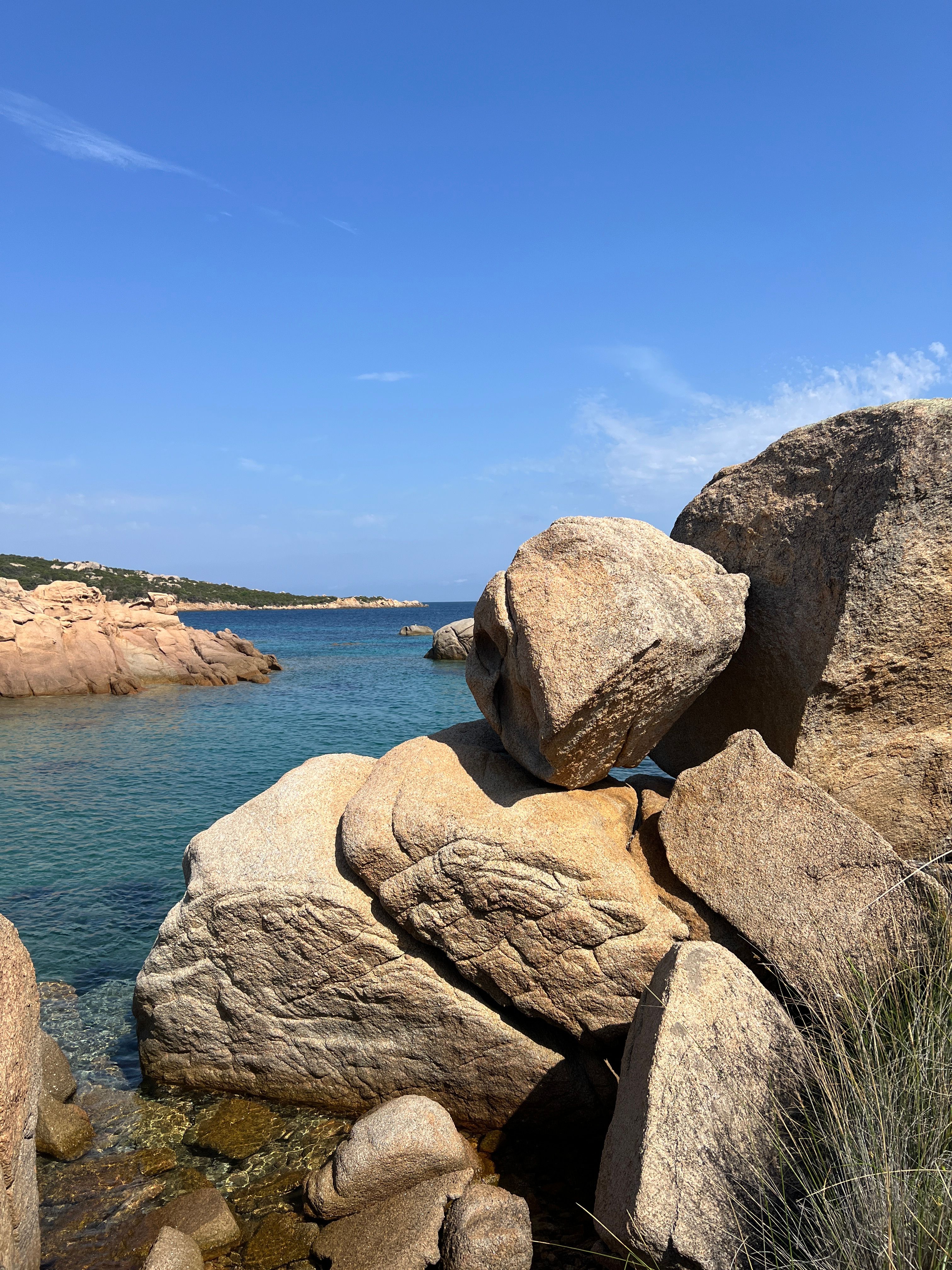 A rocky bay with clear turquoise water under a bright blue sky.
