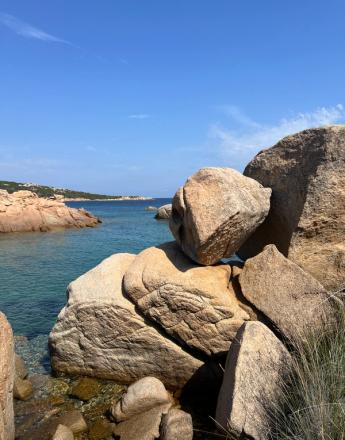 A rocky bay with clear turquoise water under a bright blue sky.