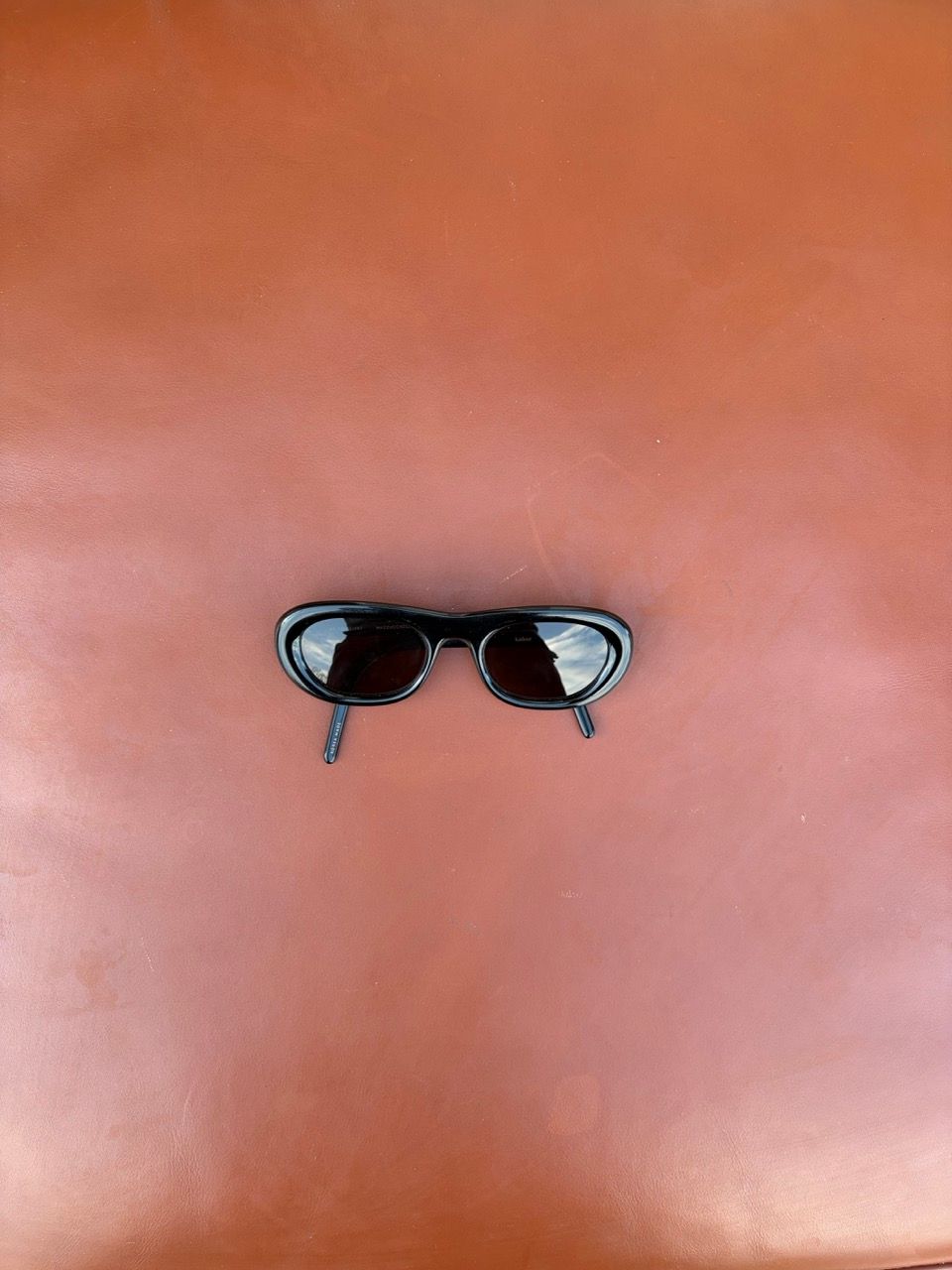 Black sunglasses on a reddish-brown background.
