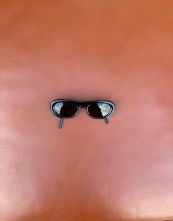 Black sunglasses on a reddish-brown background.