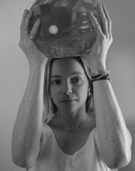 Black and white image of a woman holding a textured, mushroom-shaped object over her head.