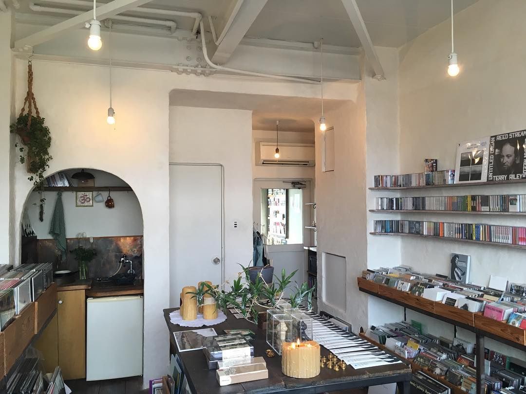 A bright, minimalist music shop with an arched kitchen nook and shelves filled with CDs and records.