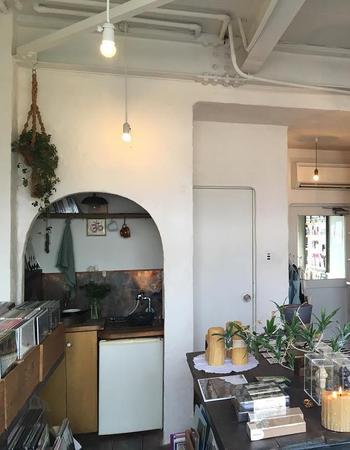 A bright, minimalist music shop with an arched kitchen nook and shelves filled with CDs and records.