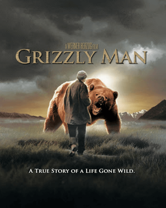Movie poster for Grizzly Man, depicting a man walking away from a roaring grizzly bear in a field with mountains. Text: A True Story of a Life Gone Wild.