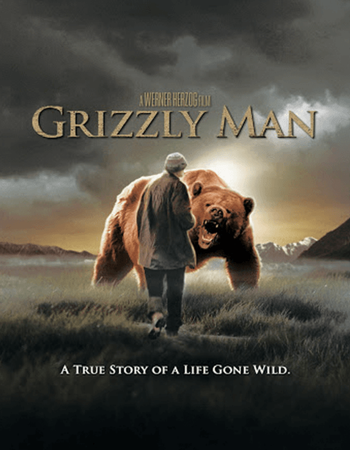 Movie poster for Grizzly Man, depicting a man walking away from a roaring grizzly bear in a field with mountains. Text: A True Story of a Life Gone Wild.
