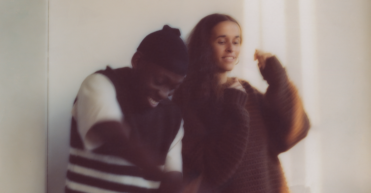 Two blurry figures, a man laughing and a woman smiling, appear to move joyfully.