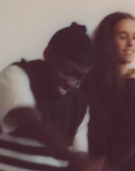 Two blurry figures, a man laughing and a woman smiling, appear to move joyfully.