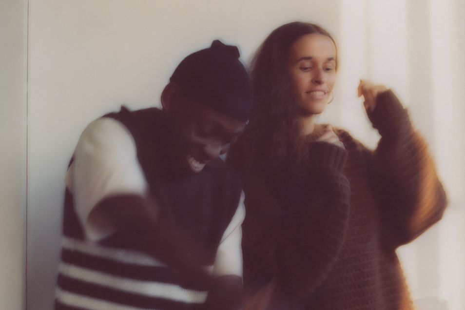 Two blurry figures, a man laughing and a woman smiling, appear to move joyfully.