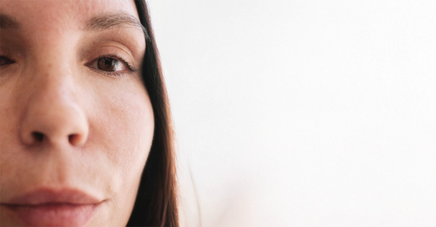 Close-up of the left half of a person's face with a brown eye, against a white background.