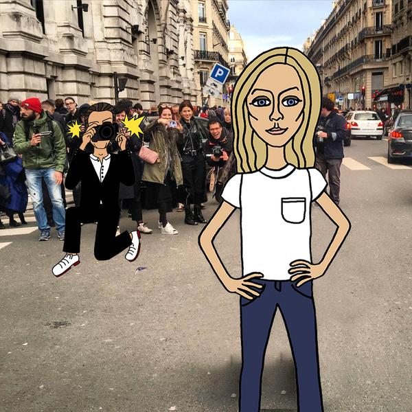 A cartoon blonde woman in a white t-shirt and jeans poses on a busy city street while a cartoon photographer snaps her picture, with real crowds and buildings in the background.