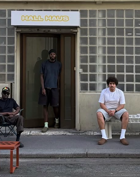 Four men in a white room displaying modular yellow panels and colorful perforated chairs.
