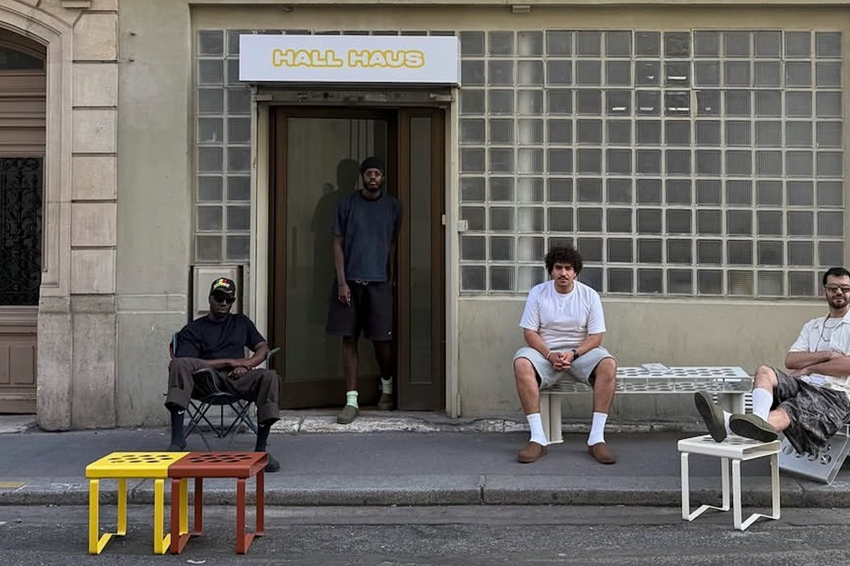 Four men in a white room displaying modular yellow panels and colorful perforated chairs.