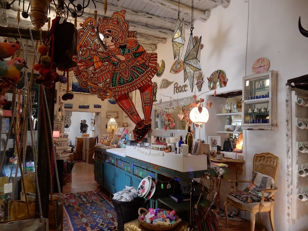 A vibrant shop interior featuring a large, colorful cutout of an Indian dancer, handmade crafts, and eclectic decor.