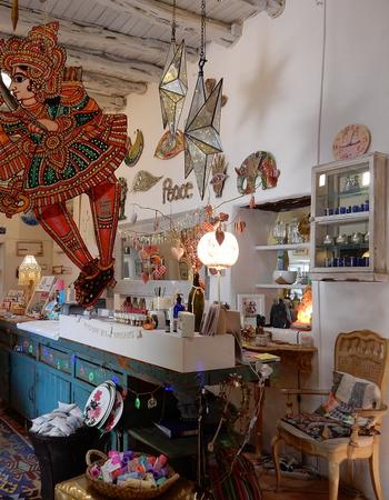 A vibrant shop interior featuring a large, colorful cutout of an Indian dancer, handmade crafts, and eclectic decor.