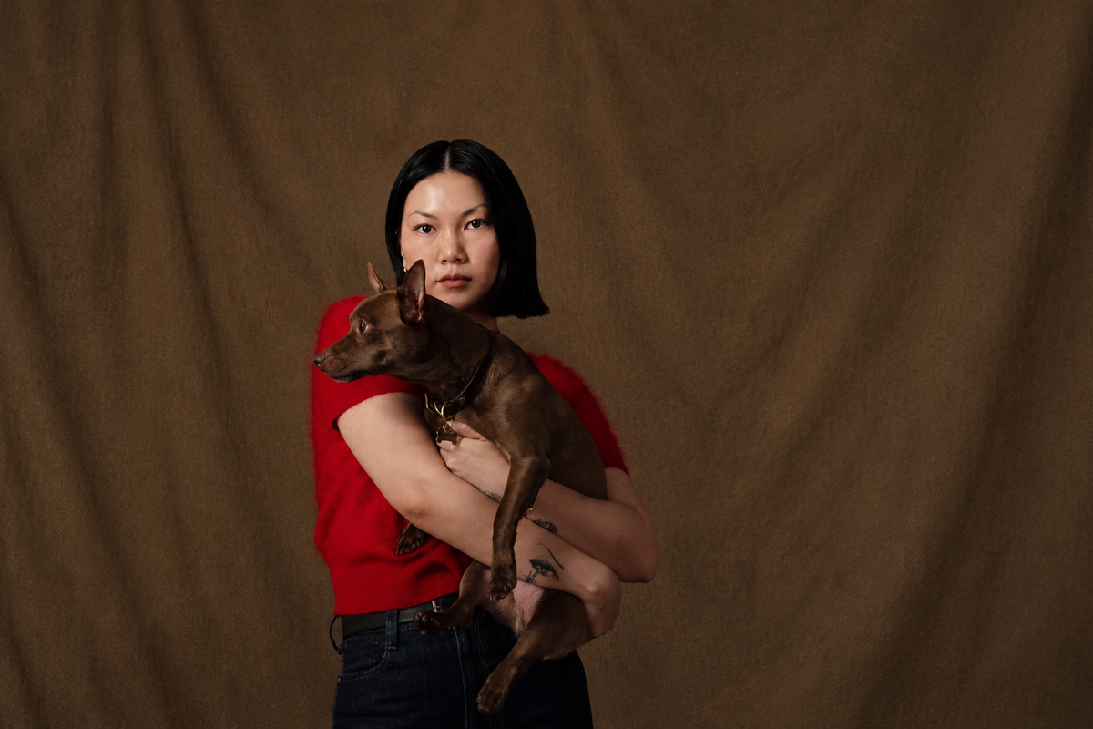 Alexandra Pauly holding her dog cam, founder of Biche dog care brand, red top brown background