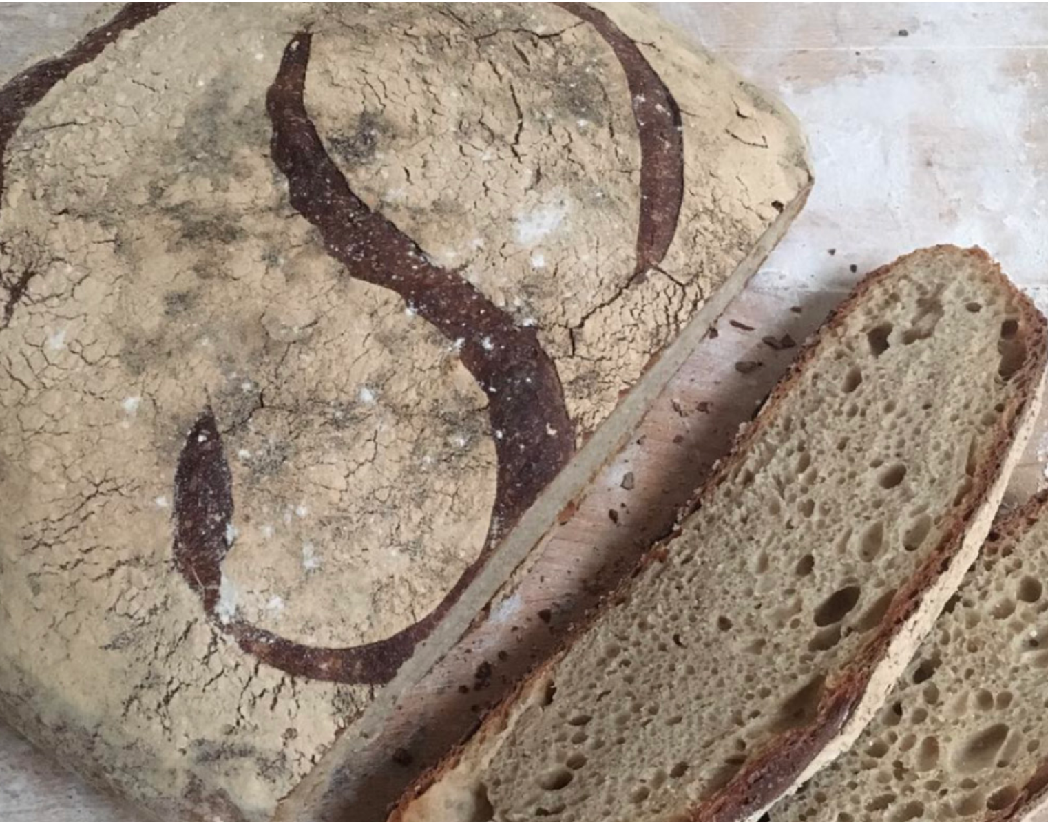 A round loaf of rustic bread with the letter "P" scored into its crust.