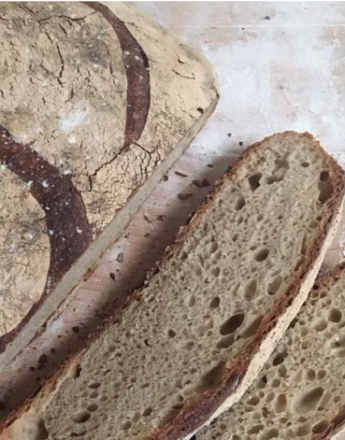 A round loaf of rustic bread with the letter "P" scored into its crust.