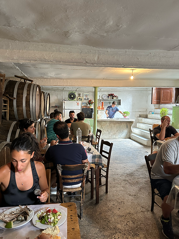 Diners enjoy a meal in a rustic restaurant featuring large wine barrels.