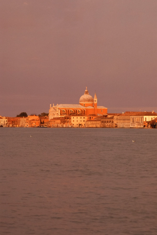 San Giorgio Maggiore church and Venice cityscape across the water at sunset.
