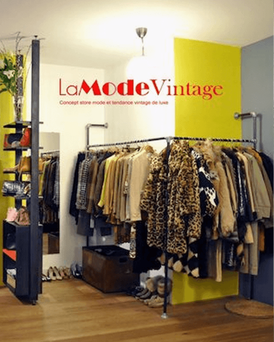 Vintage clothing store with "La Mode Vintage" sign, racks of clothes, and display shelves.