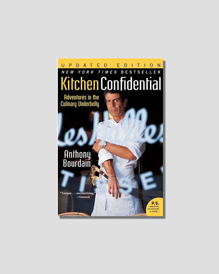 Book cover for Anthony Bourdain's "Kitchen Confidential," featuring the author in a chef's coat holding a large knife.