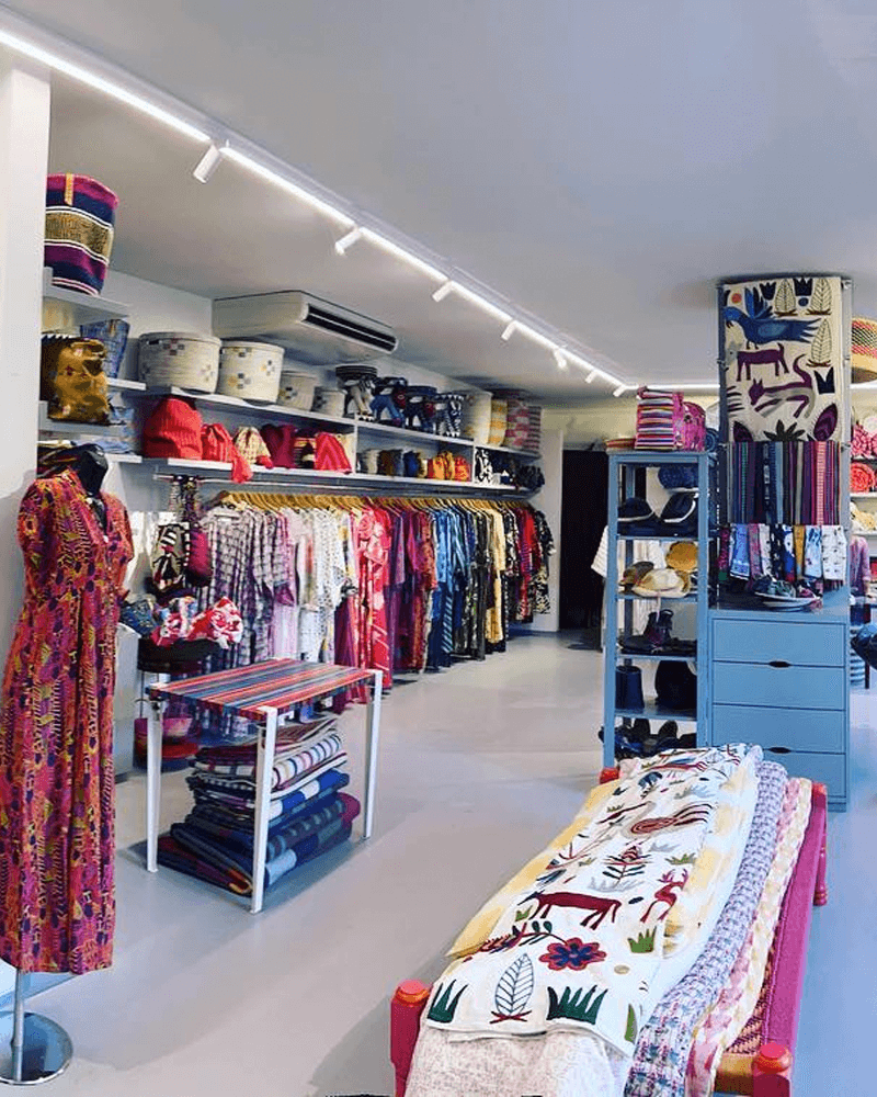 Interior of a colorful clothing and home goods boutique with racks of garments, shelves of baskets, and textiles on display.