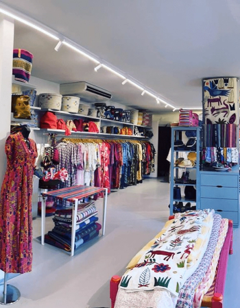 Interior of a colorful clothing and home goods boutique with racks of garments, shelves of baskets, and textiles on display.