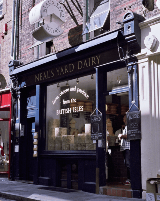 Neal's Yard Dairy storefront displaying wheels of British cheese in the window.