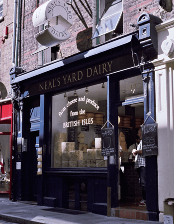 Neal's Yard Dairy storefront displaying wheels of British cheese in the window.