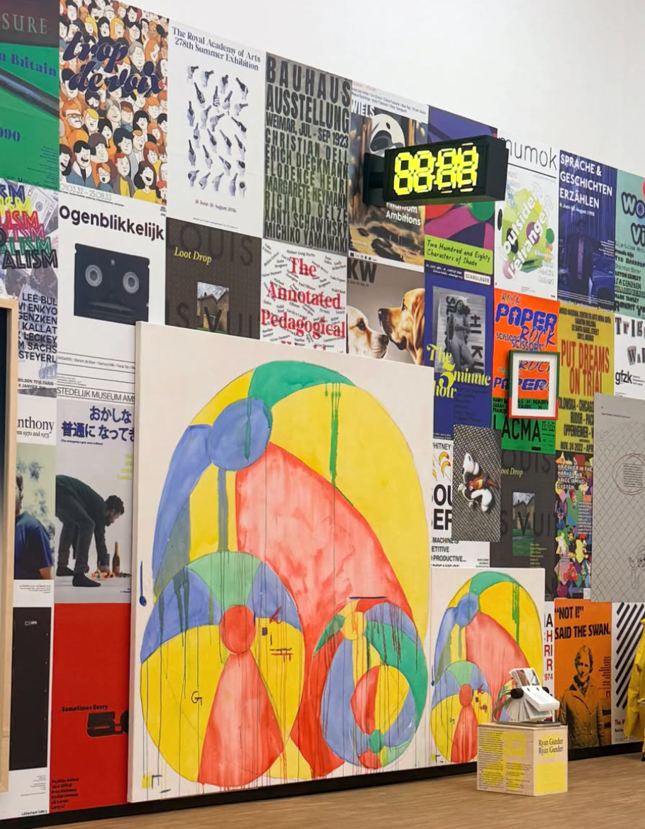 A wall filled with diverse posters displays a large painting of colorful, paint-dripped circles and a digital clock showing "88:88".