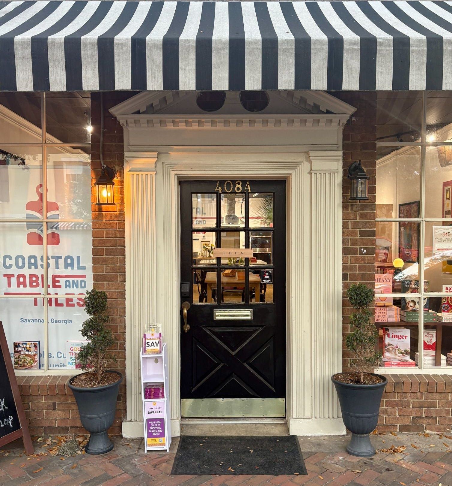Storefront with a black and white striped awning, brick facade, and a black door marked "408A" showing an "OPEN" sign.
