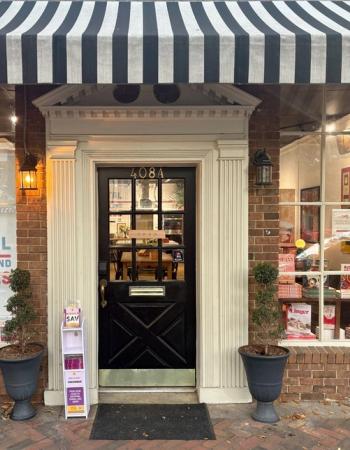 Storefront with a black and white striped awning, brick facade, and a black door marked "408A" showing an "OPEN" sign.