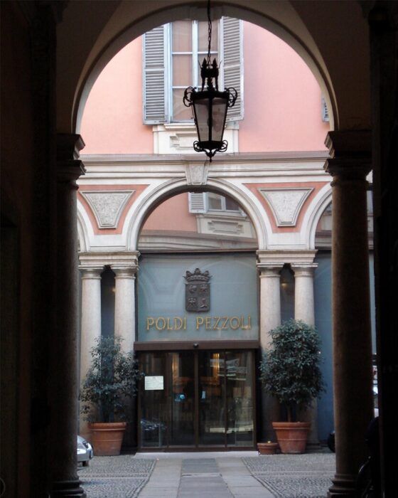 Poldi Pezzoli Museum entrance seen through an arched passage, with a hanging lantern.