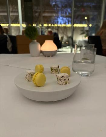 A white plate holds yellow macarons and nougat squares on a table in a restaurant.