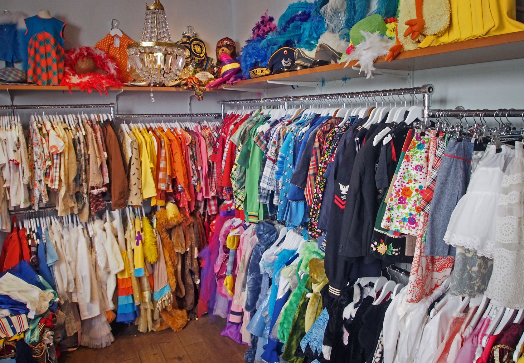 A colorful vintage clothing and costume shop filled with racks of garments and accessories.