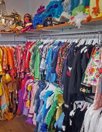 A colorful vintage clothing and costume shop filled with racks of garments and accessories.