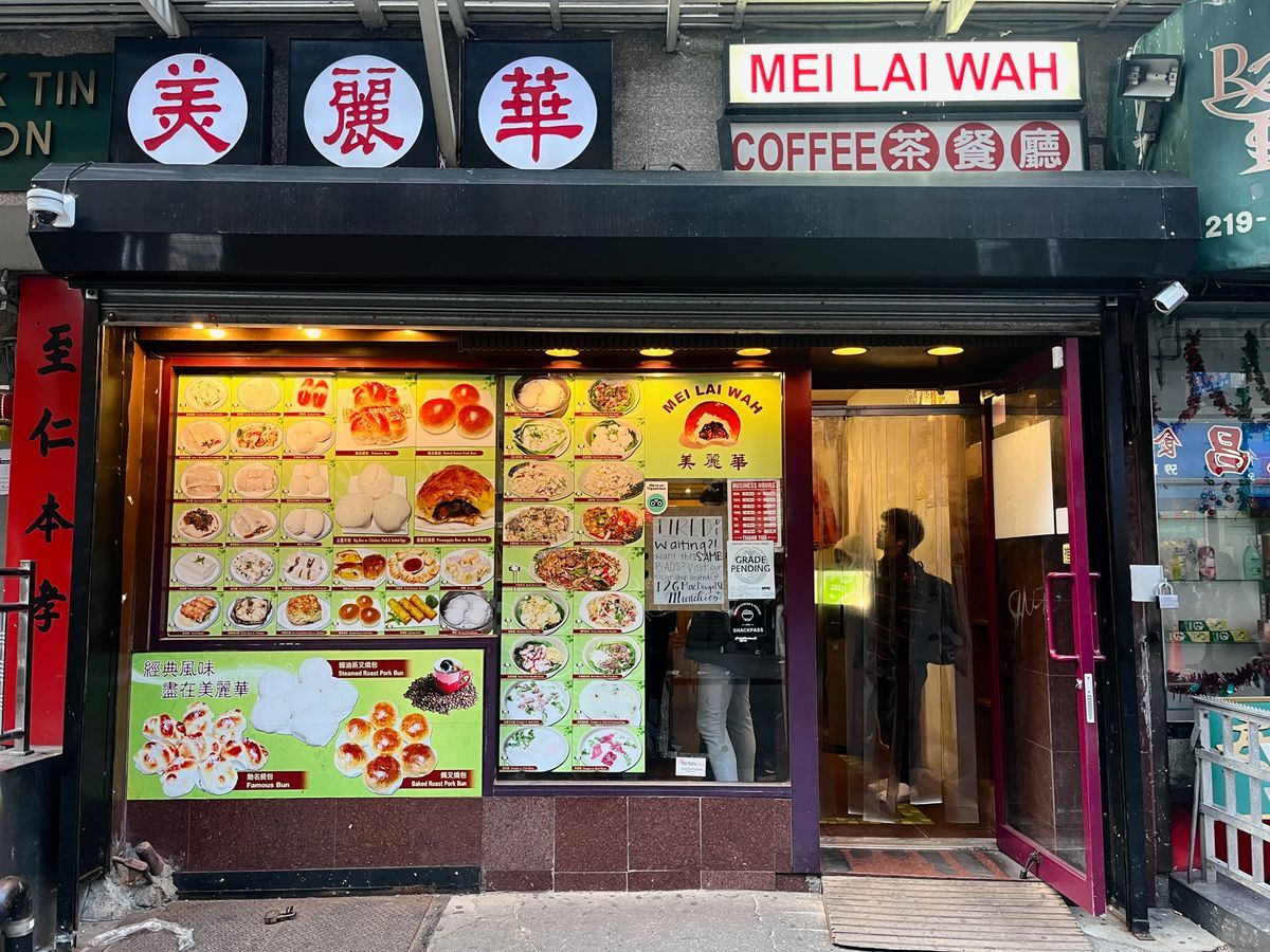 Storefront of Mei Lai Wah Chinese restaurant, with food photos displayed in the windows and an open door.