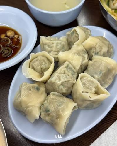 A plate of steamed dumplings with dipping sauce and soup.
